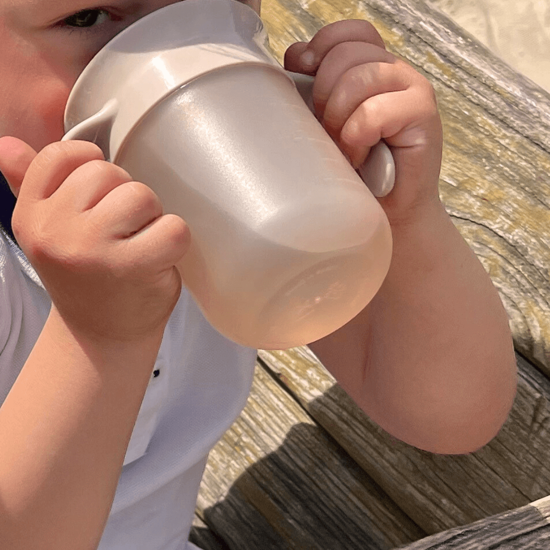 Kindje dat drinkt van de oefenbeker.