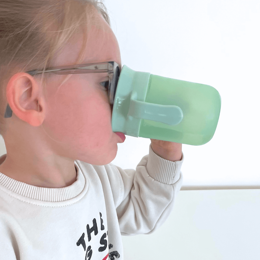 Kindje dat drinkt van de oefenbeker.